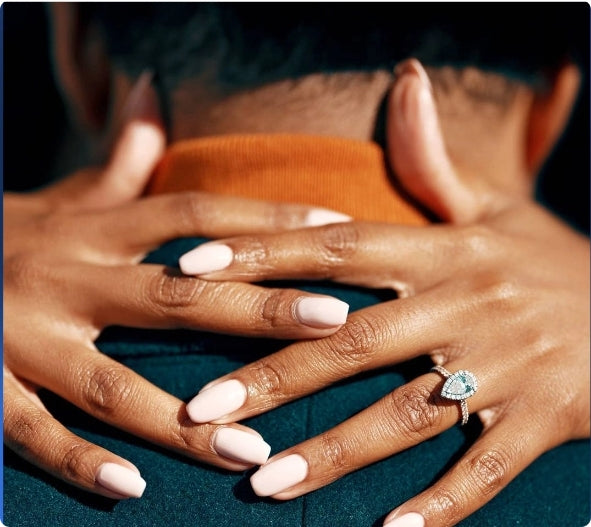 Couple standing together at sunset, the woman’s custom engagement ring catching the light